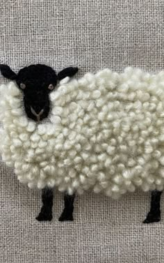 a black and white sheep standing on top of a piece of cloth