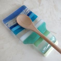 a wooden spoon sitting on top of a blue and white striped dish with stripes in it