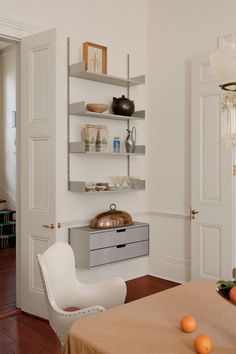 an empty dining room with white walls and open shelves on the wall next to a table