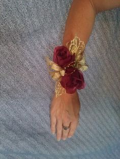 a woman's arm wearing a gold and red flower bracelet with leaves on it