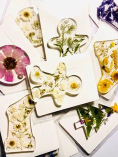 several cards with pressed flowers on them sitting on top of each other in different shapes and sizes