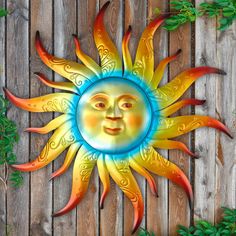 a metal sun face sitting on top of a wooden fence