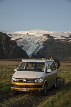 a van parked on the side of a dirt road in front of mountains and snow