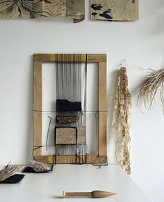 an old weaving loom is sitting on a table next to some dried plants and other items