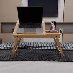 an open laptop computer sitting on top of a wooden table next to a black and white checkered blanket