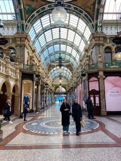 two people are standing in the middle of an indoor shopping mall with large glass ceilings