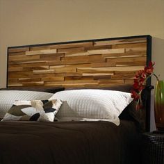 a bed with wooden headboard and pillows on top of it next to a vase filled with flowers