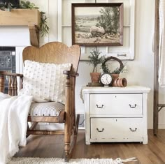 a white chair sitting in front of a fireplace next to a painting on the wall