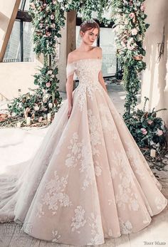 a woman in a wedding dress standing under an arch with flowers and greenery on it