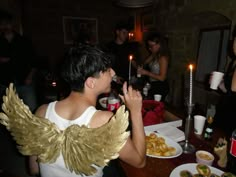 a man dressed as an angel standing in front of a table with plates of food