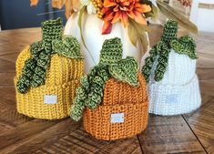 three crocheted pumpkins sitting on top of a wooden table next to each other