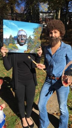 a man and woman are holding up a painting