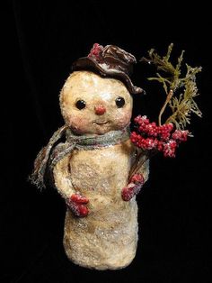 a small snowman holding some red berries