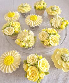 cupcakes decorated with yellow and white flowers on a clear plate