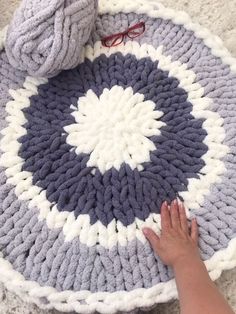 someone is crocheting a circular rug on the floor