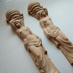 two carved wooden figures sitting next to each other