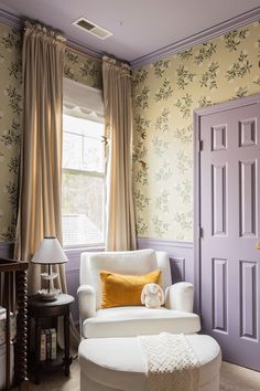 a living room filled with furniture and walls covered in floral wallpaper next to a purple door