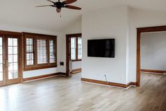 an empty living room with wood floors and large windows