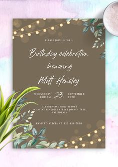 a birthday party card with greenery and lights on it, next to a cup of coffee