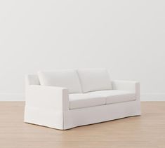 a white couch sitting on top of a hard wood floor next to a white wall