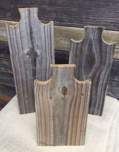 three wooden vases sitting on top of a white cloth covered table next to wood planks