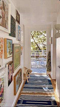 there is a hallway with pictures on the wall and a dog standing in the doorway