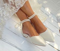 the bride's shoes are all white and have pearls on their ankle straps