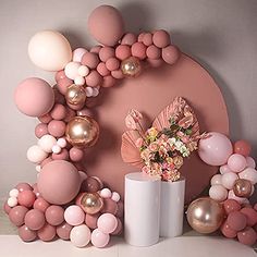 a table with balloons, flowers and vases in front of a pink circle backdrop