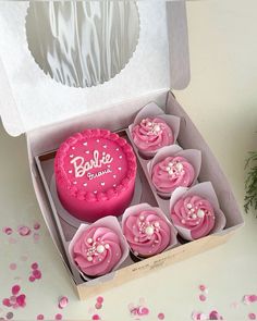 a box filled with pink frosted cupcakes on top of a table