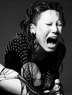 a woman with her mouth wide open and wearing large hoop earrings on her head is screaming