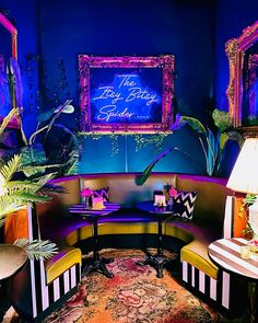 a living room filled with lots of furniture next to a wall covered in neon lights