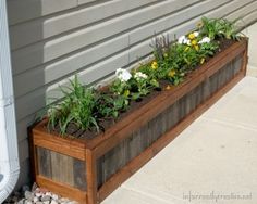 a wooden planter filled with flowers next to a house