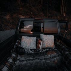 the back end of a pickup truck with pillows and blankets on it's bed