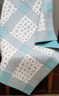 a blue and white quilt sitting on top of a wooden chair next to a wall