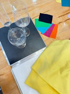 the table is covered with different colored papers and wine glasses, including one yellow napkin