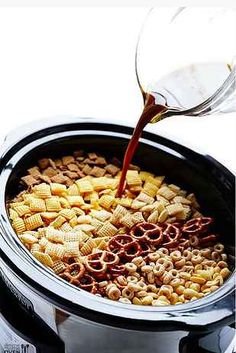 a person pouring some liquid into a crock pot filled with cheesy crackers