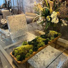 a glass table with moss and flowers on it