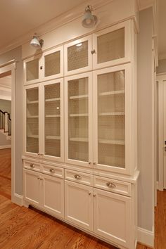 an empty room with white cabinets and wood floors in the center is lit by recessed lights