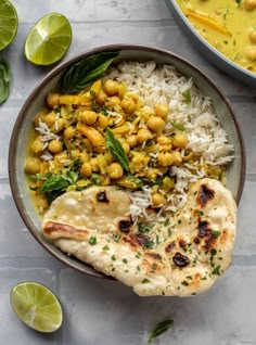 a bowl filled with rice, chickpeas and garbanzo beans next to limes