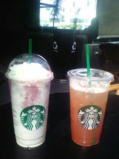 two starbucks drinks sitting next to each other on top of a black table in front of a tv