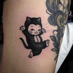 a black and white cat tattoo on the leg, with flowers in it's back