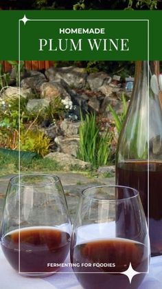 two wine glasses sitting on top of a table next to a bottle of plum wine