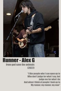 a man standing in front of a microphone while holding a guitar