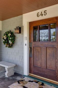 a door with a wreath on it and a bench in front