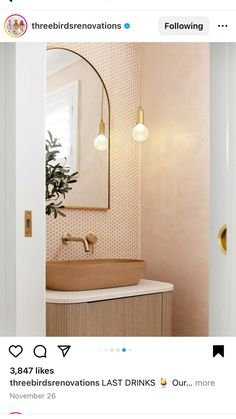 a bathroom sink sitting under a mirror next to a light fixture in a room with pink walls