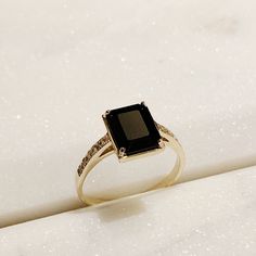 a black diamond ring sitting on top of a white surface