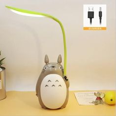 a cute little totoro lamp sitting on top of a table next to a potted plant