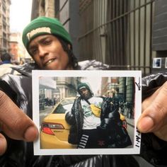 a person holding up a polaroid with a photo of a man in the background