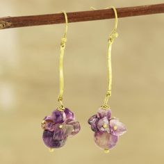 two small purple flowers are hanging from gold earwires