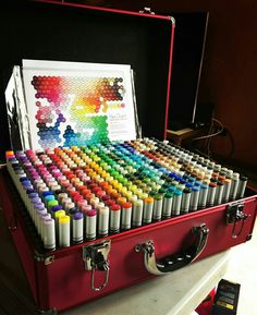 an open red suitcase filled with lots of different colored crayons and watercolors